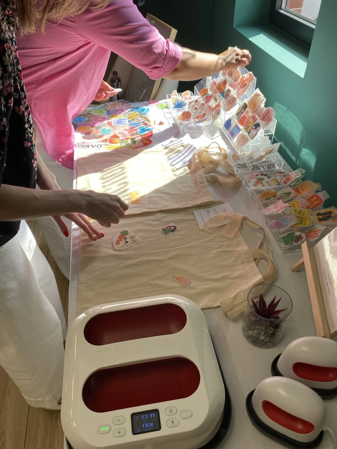 Mâini alegând designuri și pregătind produse la standul Printello